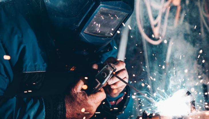 رجل يقوم بتلحيم قطعة حديدية.