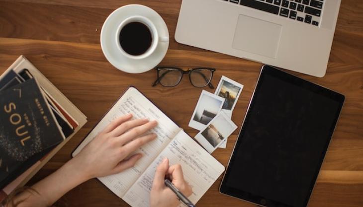 صورة لشخص يقوم بتدوين وتنظيم ملاحظات في دفتر يومياته.